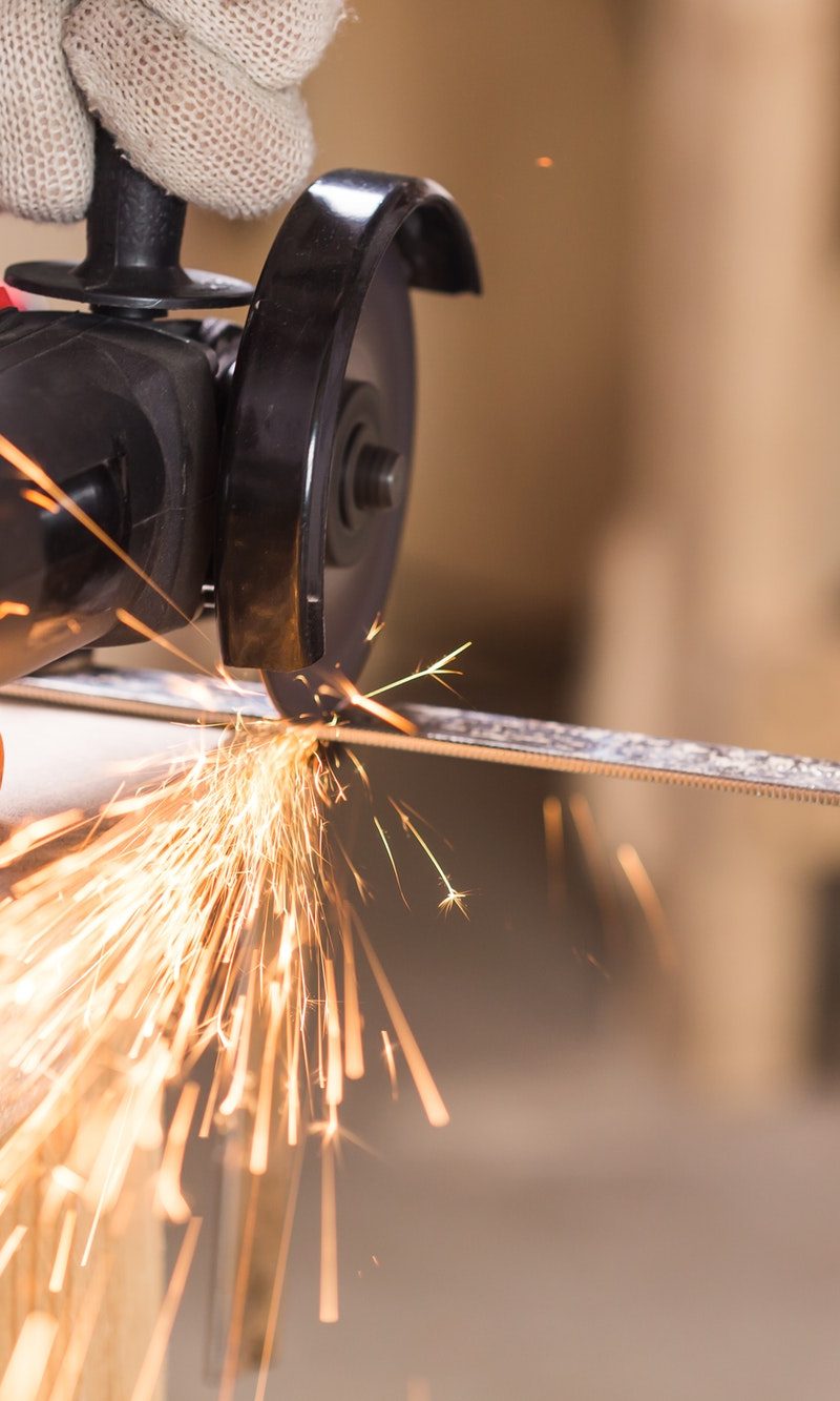Heavy industry worker cutting steel with angle grinder Heavy industry worker cutting steel with angle grinder